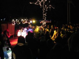 Crowd gathered outdoors at night with festive lights.