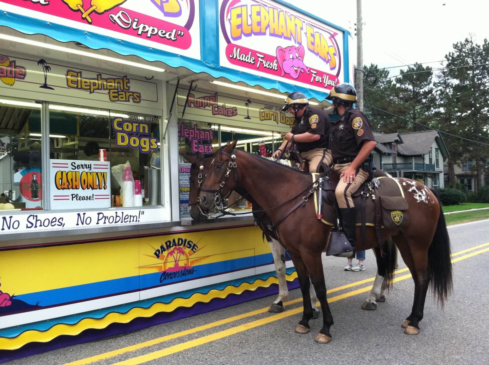 Mounted police at food stand with carnival treats.