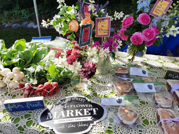 Farmers market table with flowers and fresh produce.
