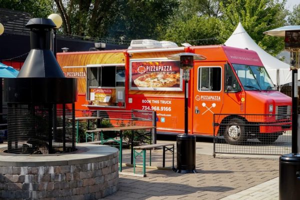 Colorful pizza food truck parked outdoors at festival.