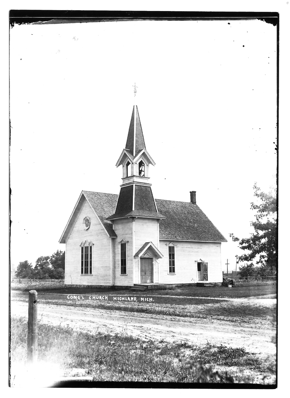 Historic white church with steeple in rural setting.