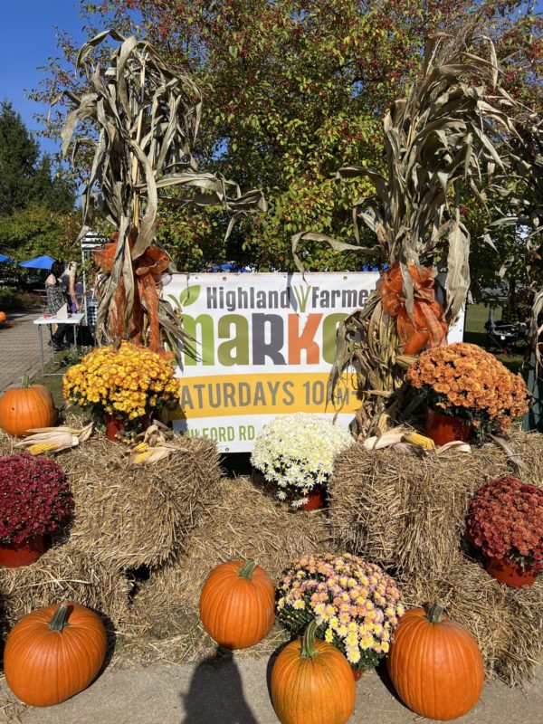 Farmers market fall display with pumpkins and flowers.