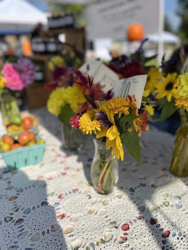 Farmers market table with fresh flowers and produce.