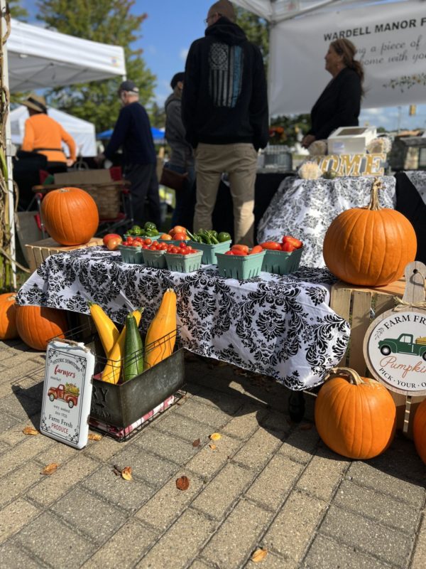 Farmers market stand with pumpkins and fresh produce.