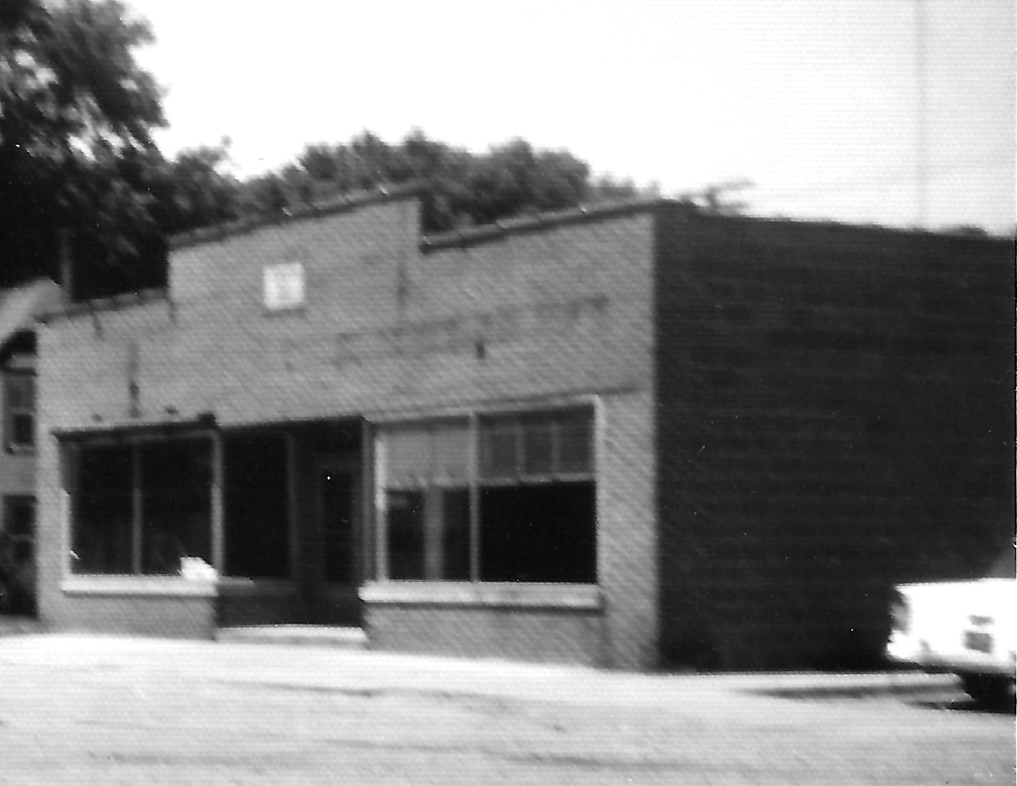 Vintage brick building with large windows and classic car.