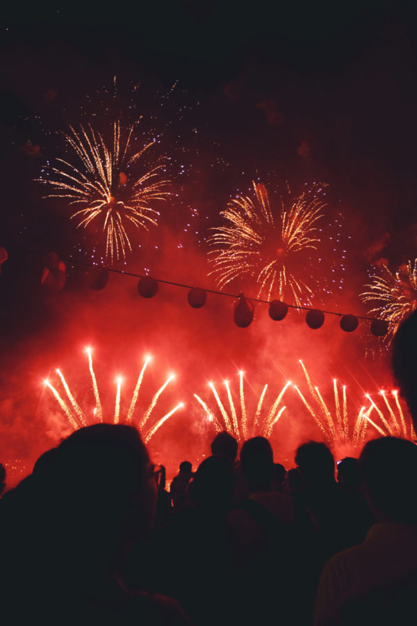 Red fireworks display with silhouetted crowd below.